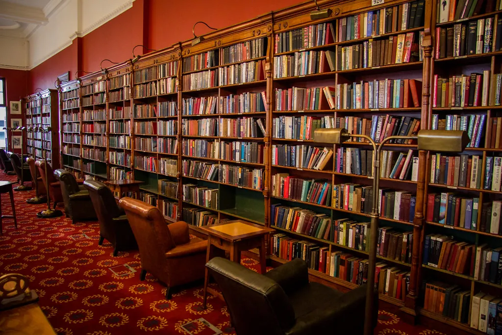Biblioteca con estantes altos llenos de libros y sillones de lectura